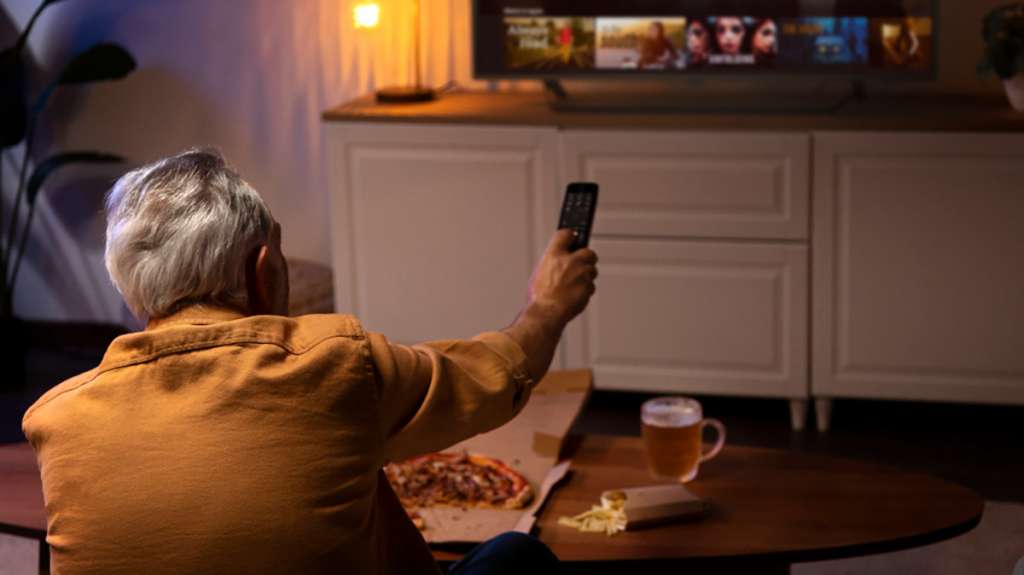 Starszy mężczyzna trzymający pilot do telewizora - zdjęcie ilustracyjne