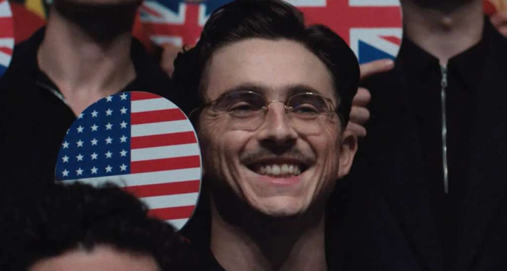 Timothée Chalamet w filmie Marty Supreme trzymający ping pongową paletkę z flagą USA 