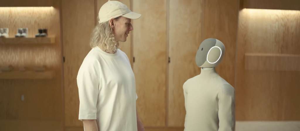 Człowiek rozmawia z humanoidalnym robotem NEO od 1X Technologies w nowoczesnym wnętrzu – interakcja człowieka z AI.